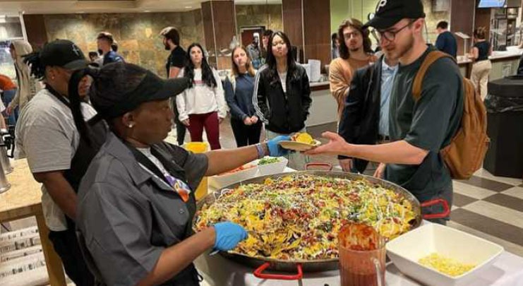 Parkhurst Dining chefs serve higher education students from a large skillet.